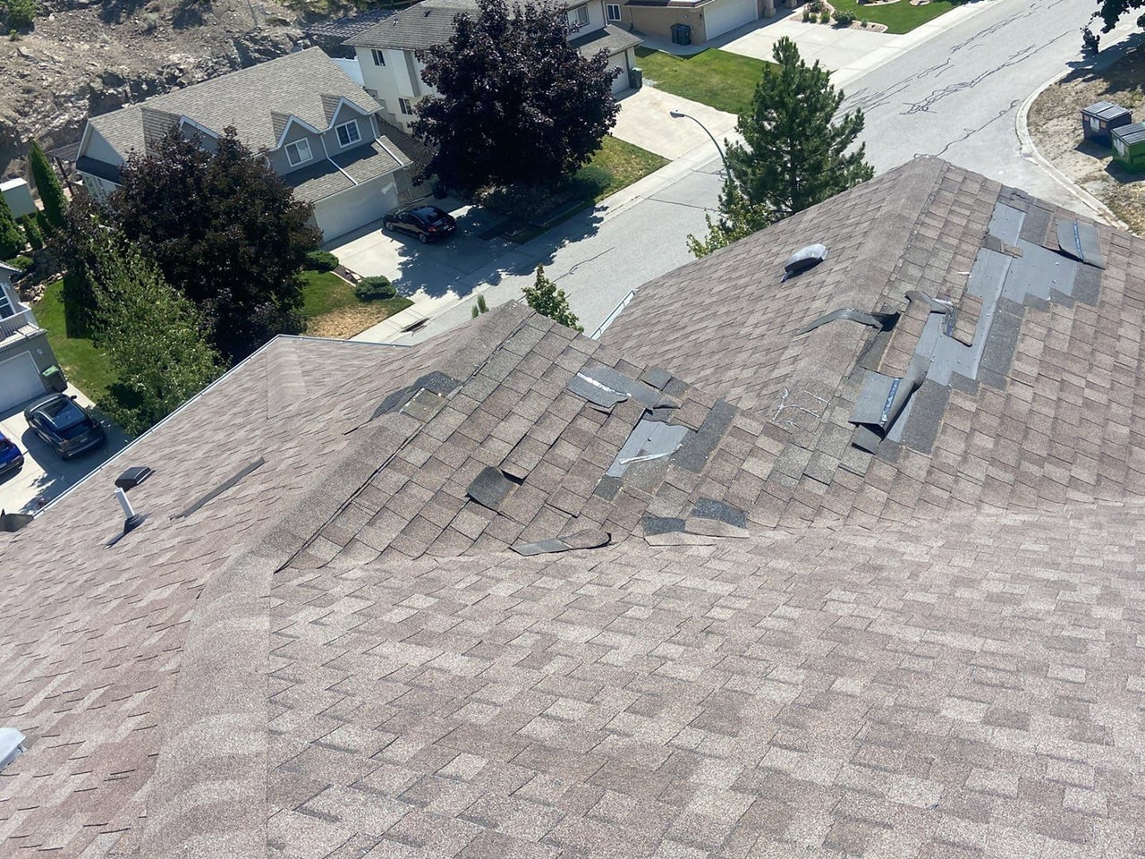 Aerial view of a Kelowna roof with a band of shingles peeled back by wind